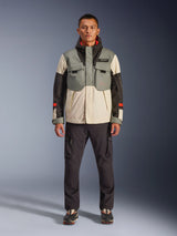 Alpinestars Mospher Waterproof Jacket in Fur Gray Black Ice, tactical-style motorcycle parka worn by a male model with dark cargo pants, multi-pocket design with color-blocked gray, cream, and black panels, urban commuter riding gear