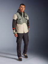 Alpinestars Mospher Waterproof Jacket in Fur Gray Black Ice, multi-colored technical motorcycle parka with gray, black, and off-white panels and red accents, utility-driven design with large pockets and hood, worn with dark gray cargo pants and black sneakers, urban contemporary motorcycle gear