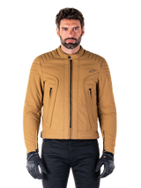Alpinestars Clayton WR Jacket, Urban Motorcycle Jacket, Utility Brown Light Gold, water-resistant textile with quilted padded shoulders, high biker collar, black zipper details, and chest logo, worn with black protective gloves and pants