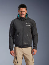 Alpinestars Moblast Waterproof Jacket, Men's Urban Motorcycle Jacket, Black with Teal Hood Lining, features 3D zip pockets and hooded design, worn with tan cargo pants, modern urban motorcycle apparel