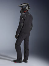 Motorcyclist wearing the Alpinestars Andes Pro Drystar® XF Jacket and matching pants in Black and Dark Gray, back view profile, featuring a black carbon-fiber adventure helmet, black gloves, and adventure boots, high-performance coordinated gear for adventure touring.