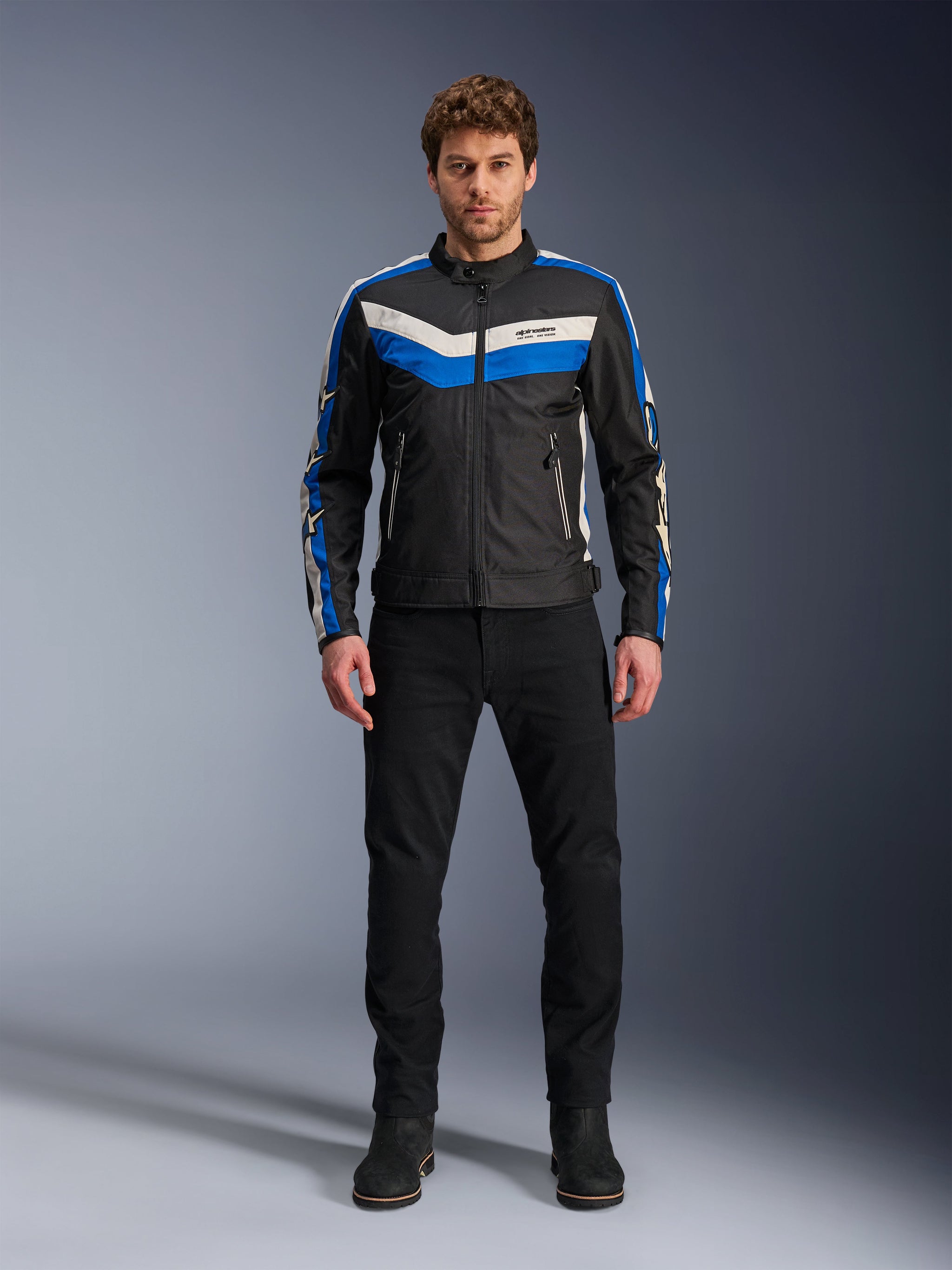 Alpinestars T-Dyno WR Jacket, Textile Motorcycle Jacket, Black Blue and Ecru, worn by male model with black pants and boots, featuring chevron stripes on the chest and heritage biker design
