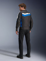 Alpinestars T-Dyno WR Jacket in Black Blue Ecru, back view on a male model, featuring a white and blue chevron stripe across the shoulders with a star logo, vintage-inspired textile motorcycle jacket, worn with black pants and boots