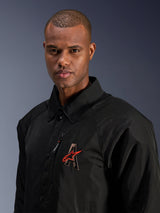 Alpinestars Revved WR Jacket, Black, close-up shot of a man wearing the water-resistant satin motorcycle jacket, featuring 3D embroidered 'A' logo with red Alpinestars star, zippered chest pocket, and collared design for urban contemporary riding.