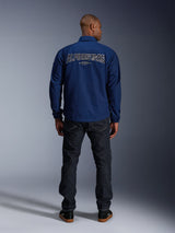 Alpinestars Revved WR Jacket in Navy Blue, rear view, featuring large 3D effect 'ALPINESTARS' embroidery across the back, styled with dark denim jeans and black sneakers, urban motorcycle apparel.