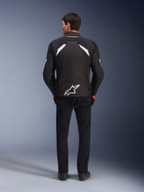 Alpinestars T-GP R V3 Drystar® Jacket, Black and White, rear view, waterproof textile motorcycle jacket featuring a large white star logo on the lower back and white accents on the shoulders, paired with black pants and boots, race-derived sport design