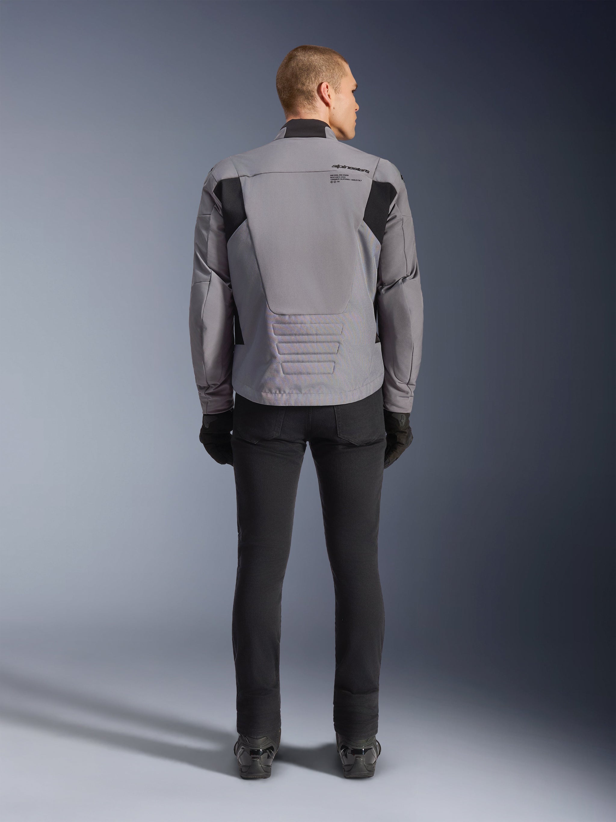 Alpinestars SMX Waterproof Jacket, Rear view, Dark Gray and Black, featuring black textile panels on shoulders and a sport-fit design, paired with black pants and gloves for a complete motorcycling look