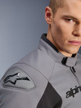 Close-up detail of the Alpinestars SMX Waterproof Jacket in Dark Gray Black, highlighting the DFS Lite shoulder slider with the Alpinestars logo, sport collar, and durable textile material.