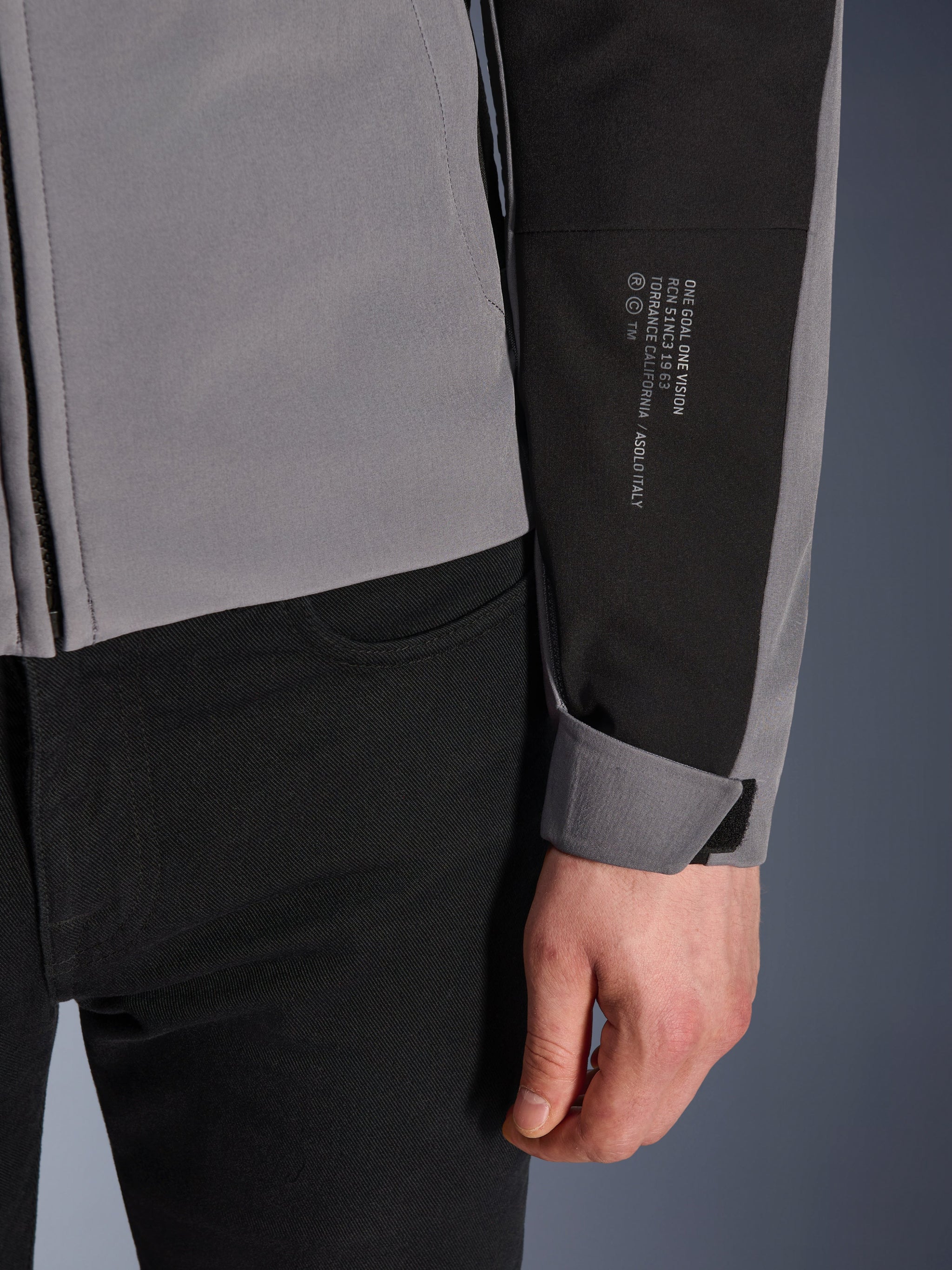 Alpinestars SMX Waterproof Jacket, Dark Gray and Black, close-up of sleeve featuring white printed text with brand heritage details, adjustable Velcro cuff, sporty textile design for all-weather motorcycle riding