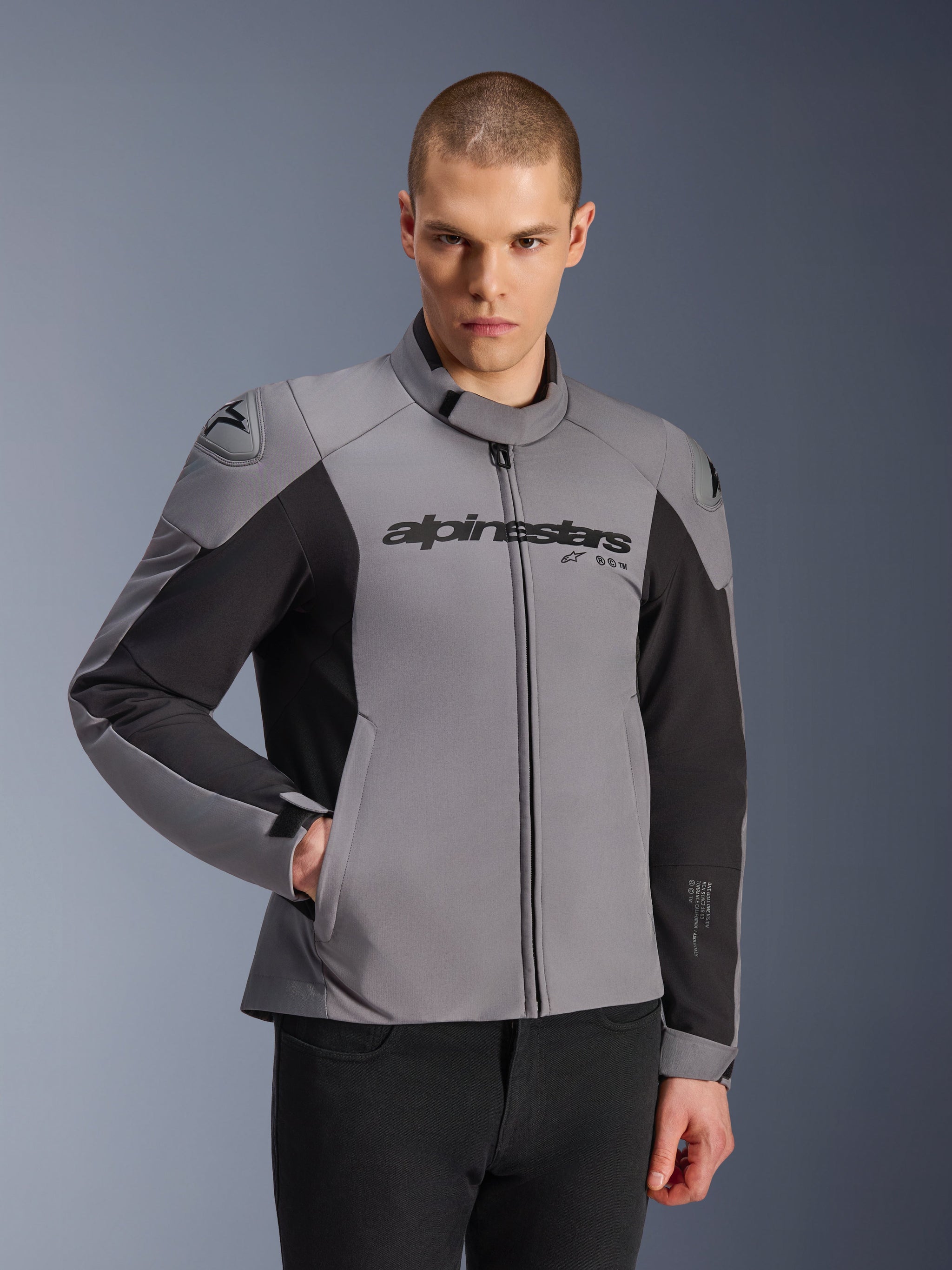 Alpinestars SMX Waterproof Jacket, Dark Gray and Black, worn by a male model, featuring 'alpinestars' branding on the chest, DFS Lite shoulder protection, sleek sport design with textile and softshell materials for road riding.