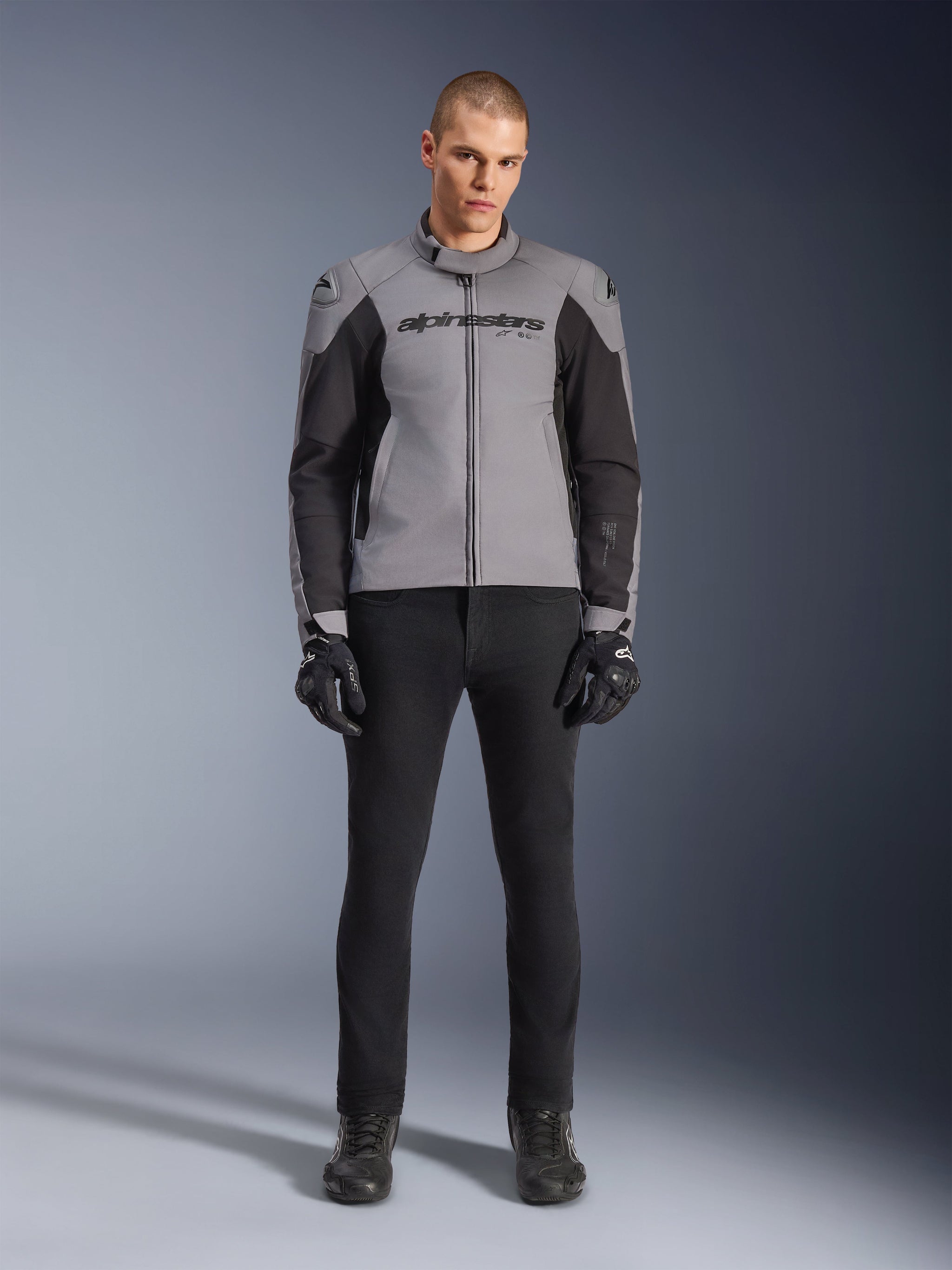 Alpinestars SMX Waterproof Jacket, Dark Gray and Black, front view worn by a male model, textile sport motorcycle jacket featuring black side panels and Alpinestars branding on the chest, paired with black riding pants and gloves.