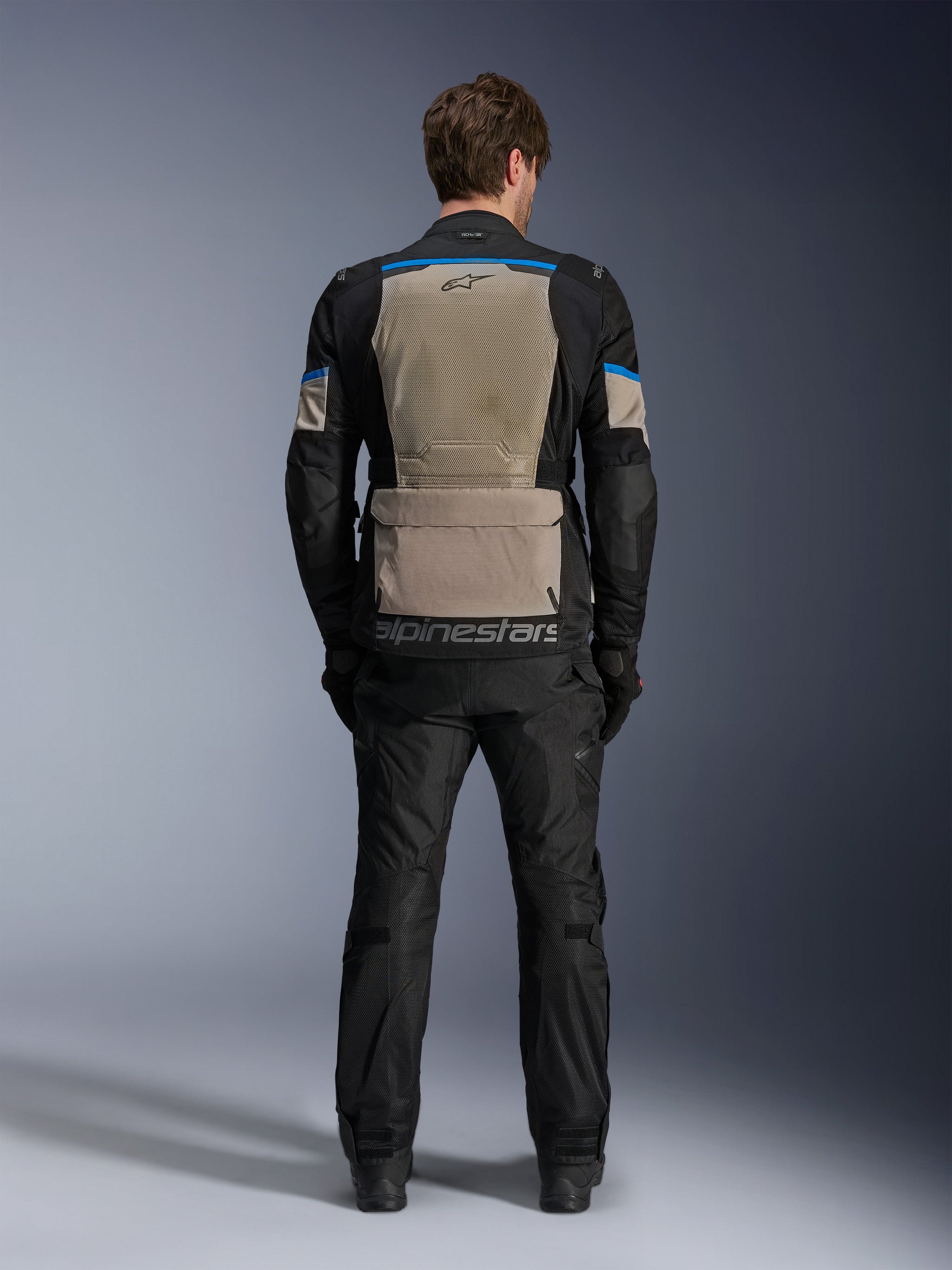 Alpinestars Andes Air Drystar® Jacket, Black Laurel Gray Bright Blue, rear view showing extensive mesh ventilation panel, large lower back storage pocket with Alpinestars branding, technical motorcycle touring jacket worn with matching trousers.