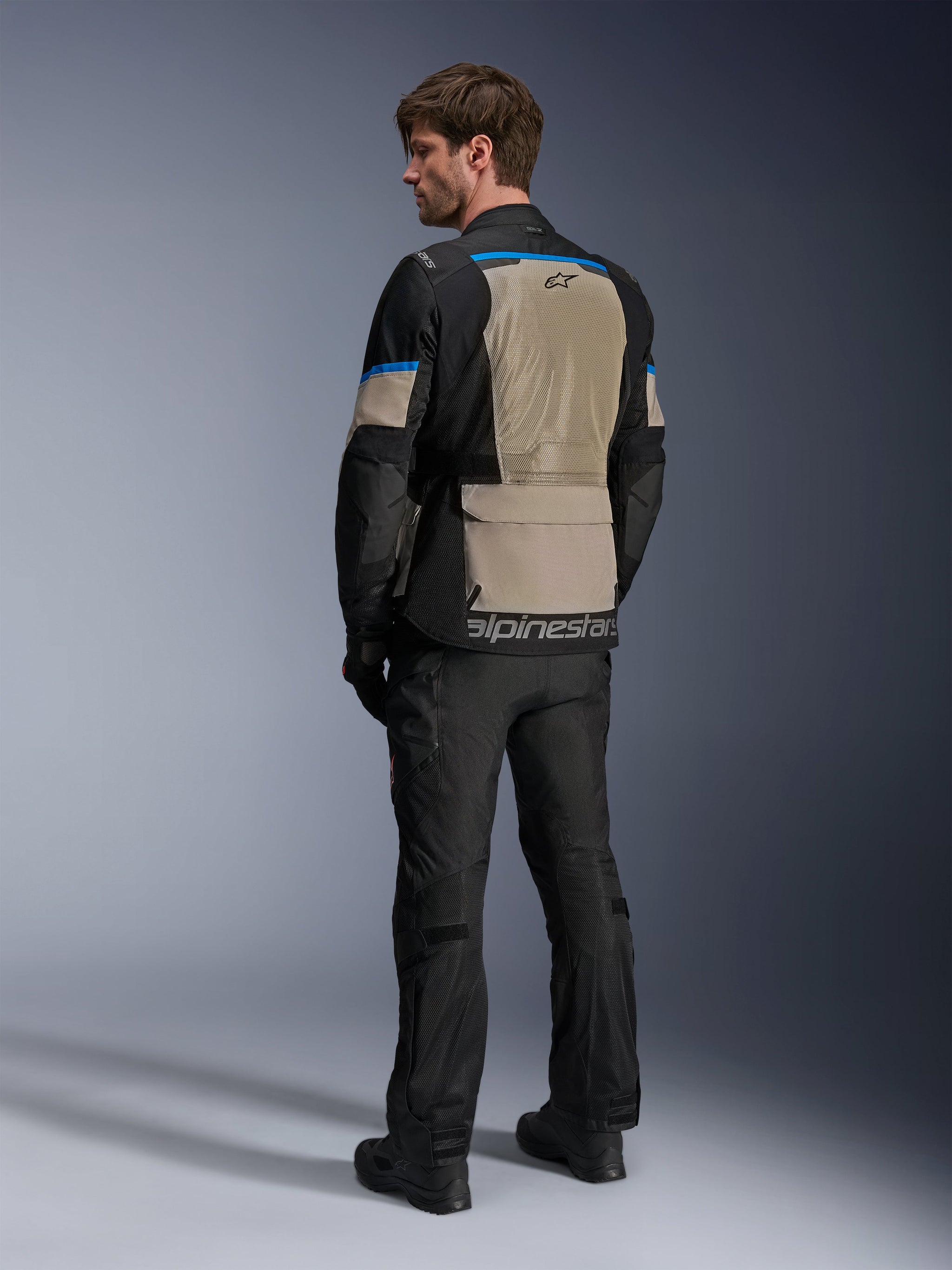 Alpinestars Andes Air Drystar® Jacket, Black Laurel Gray and Bright Blue, rear view showing large mesh ventilation panel on the back, logo on lower hem, worn with black motorcycle pants and boots.