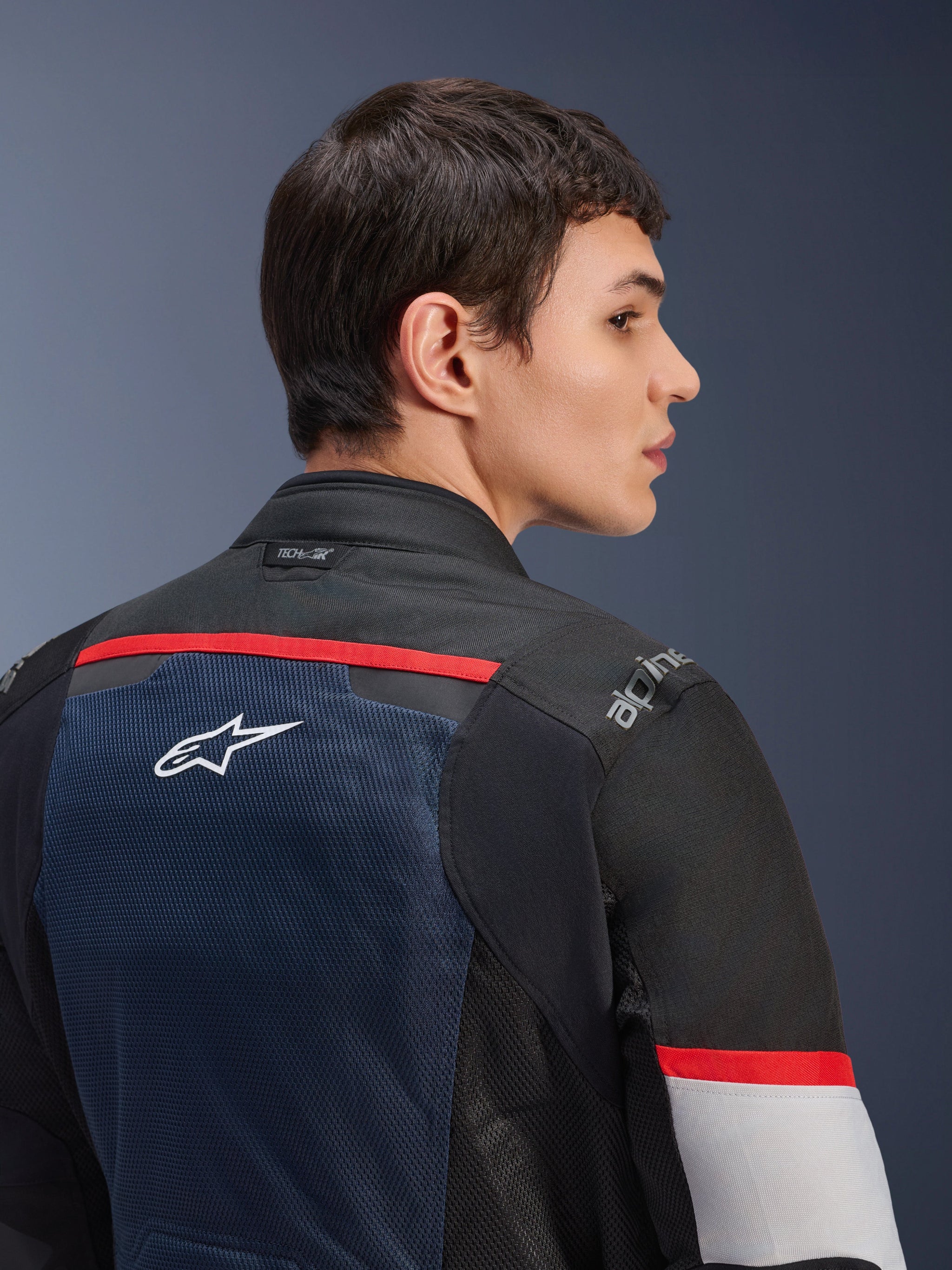 Alpinestars Andes Air Drystar® Jacket, Deep Blue Black and Ice Gray, close-up back view on a model, featuring a breathable mesh panel with white star logo, red accents, and Tech-Air® branding on the collar, dual-season touring motorcycle gear
