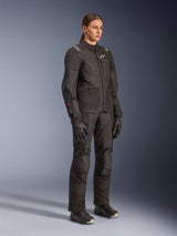 Female rider wearing the Alpinestars Woman Stella Andes V4 Drystar® Jacket in black, paired with matching adventure touring pants, gloves, and boots, featuring white Alpinestars logos and red Drystar branding, designed for all-weather motorcycle performance.