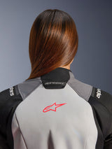 Alpinestars Woman Stella Andes V4 Drystar® Jacket, close-up of the upper back and collar, ice gray textile with a coral fluo star logo, black and dark gray panels, worn by a rider with long brown hair.