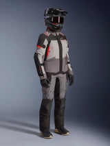 Alpinestars Stella Andes V4 Drystar® Jacket, Women's Adventure Motorcycle Jacket, Dark Gray Ice Gray and Black with Coral Fluo accents, worn by a rider in a full gear set with matching gray pants, black adventure helmet with goggles, and black gloves.