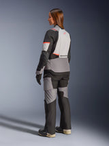 Woman wearing the Alpinestars Stella Andes V4 Drystar® Jacket in Dark Gray, Ice Gray, Black, and Coral Fluo, rear view, paired with matching adventure motorcycle pants and boots, showcasing the sleek modern design and high-visibility accents.