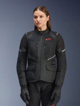 Alpinestars Stella Andes Air Drystar Jacket, Women's Motorcycle Touring Jacket, Black with gray accents and a small red logo, featuring mesh ventilation panels, a high collar, and multiple utility pockets, worn with matching riding gloves and pants