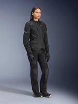 Woman wearing Alpinestars Stella Andes Air Drystar® Jacket, Black textile adventure touring jacket, worn with matching black pants and gloves, featuring large mesh ventilation panels and a red logo, coordinated outfit for women's motorcycle riding