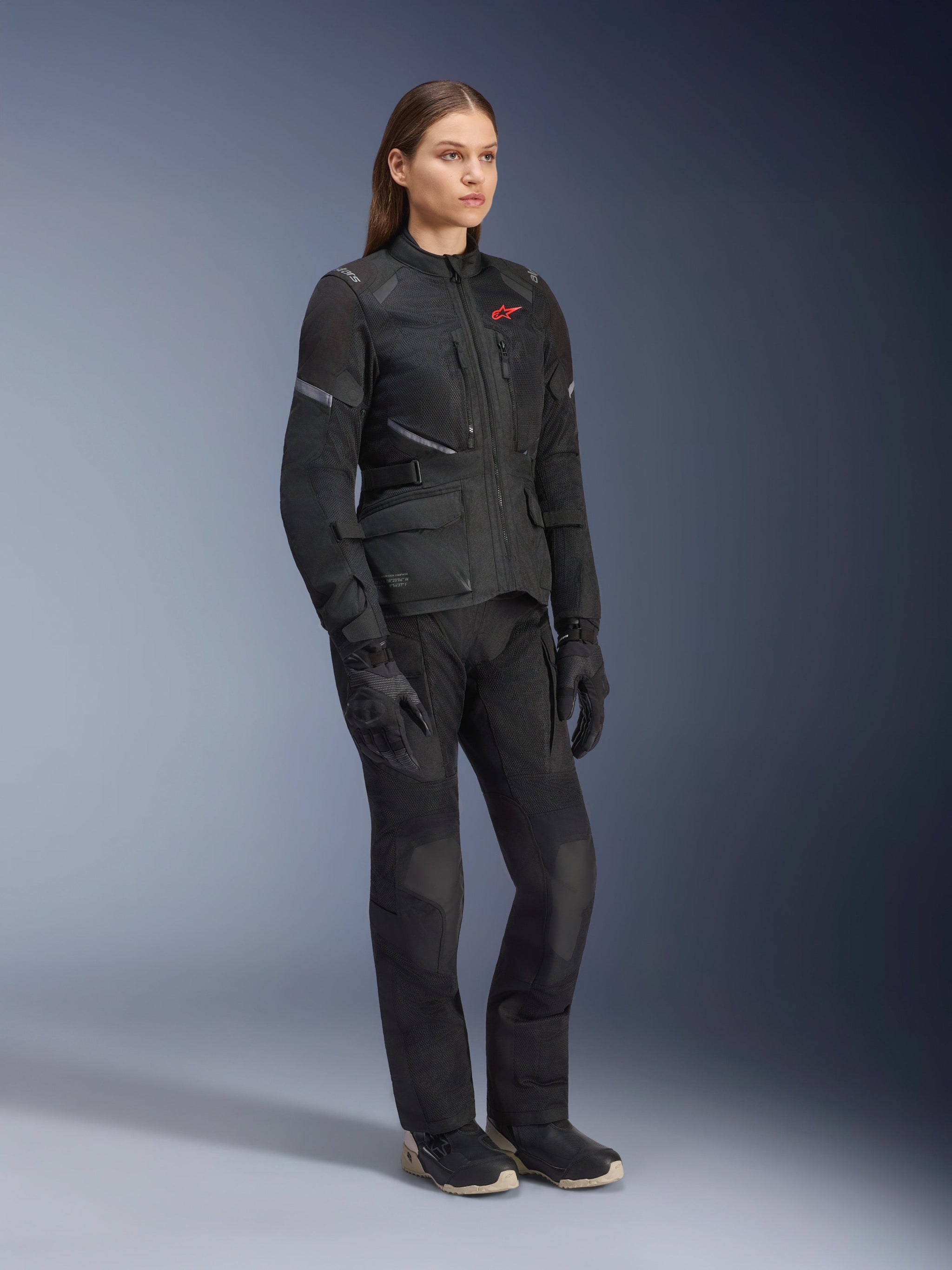 Woman wearing Alpinestars Stella Andes Air Drystar® Jacket, Black textile adventure touring jacket, worn with matching black pants and gloves, featuring large mesh ventilation panels and a red logo, coordinated outfit for women's motorcycle riding