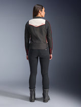 Rear view of a female model wearing the Alpinestars Stella T-Dyno WR Jacket in Black Ecru Bright Red, featuring a prominent cream back panel and red logo accents, styled with black pants and boots, a vintage-inspired textile motorcycle jacket.