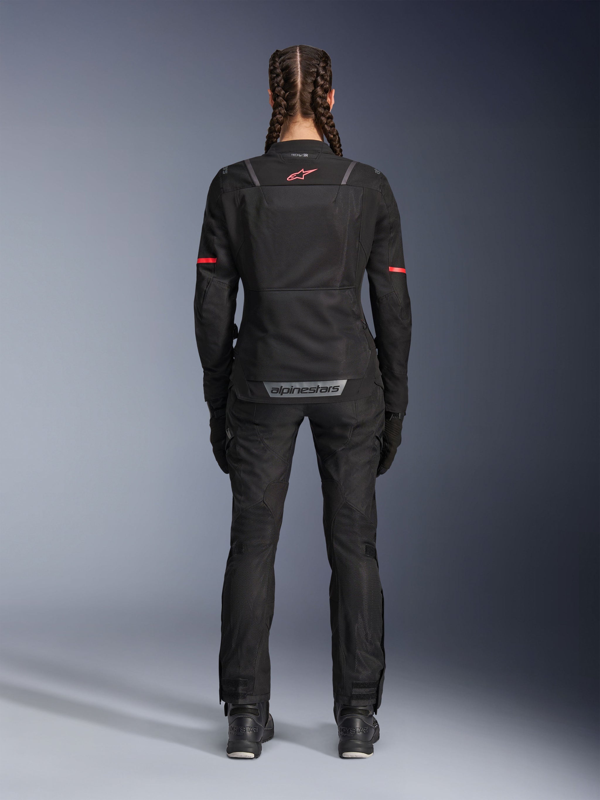 Alpinestars Stella ST-2 Air Jacket, Women's Motorcycle Jacket, Black, rear view featuring red logo on upper back and grey branding on lower back, worn with matching black riding pants and boots, modern touring design with mesh panels and reflective details