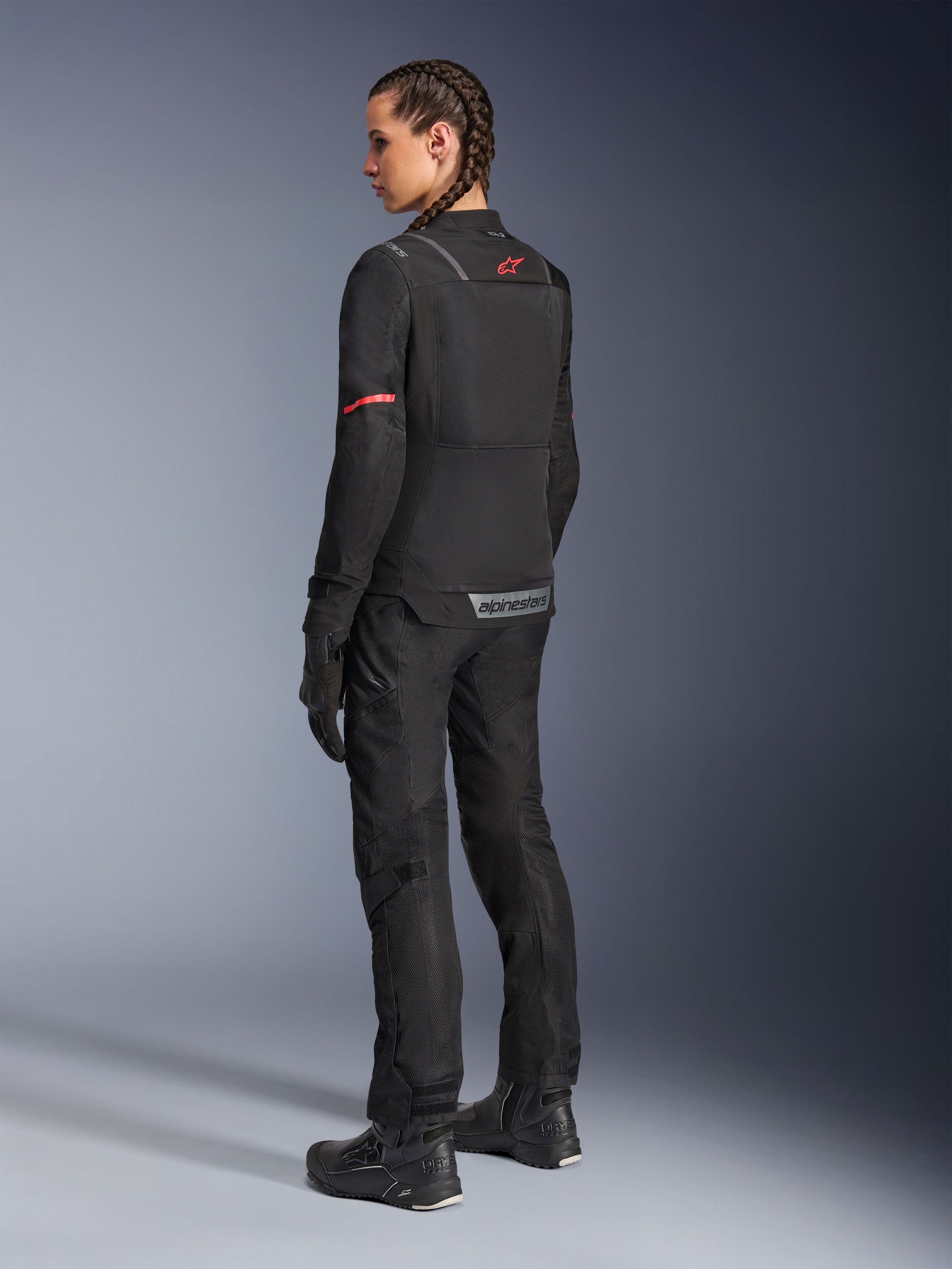 Alpinestars Stella ST-2 Air Jacket, Women’s Motorcycle Jacket, Black with red accents on sleeves and upper back, rear view on model wearing matching black motorcycle pants and boots, featuring reflective Alpinestars branding and modern textile construction.