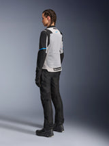 Female rider wearing the Alpinestars Stella ST-2 Air Jacket in Ice Gray and Black, rear three-quarter view highlighting the large light gray mesh back panel, black sleeves with a blue accent stripe, and a blue Alpinestars logo, paired with black riding pants, gloves, and boots for a complete adventure touring outfit