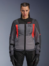 Alpinestars Stella ST-2 Air Jacket, Women's Motorcycle Jacket, Deep Gray and Fluo Coral, model wearing ventilated textile jacket with mesh panels, bright coral accents and chest branding, modern adventure riding style