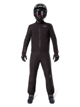 Motorcycle rider wearing Alpinestars AMT-8 Stretch Drystar® XF Pant Liner and matching jacket, all-black waterproof and windproof technical gear, featuring a black helmet, gloves, and boots, sleek adventure touring design.