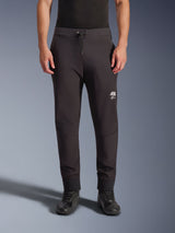 Alpinestars Aeroshell Pants, Black softshell motorcycle pants, jogger-style athletic fit with drawstring waist and elastic cuffs, featuring a white Astars logo, worn with black riding shoes, modern crossover gear for road and casual use