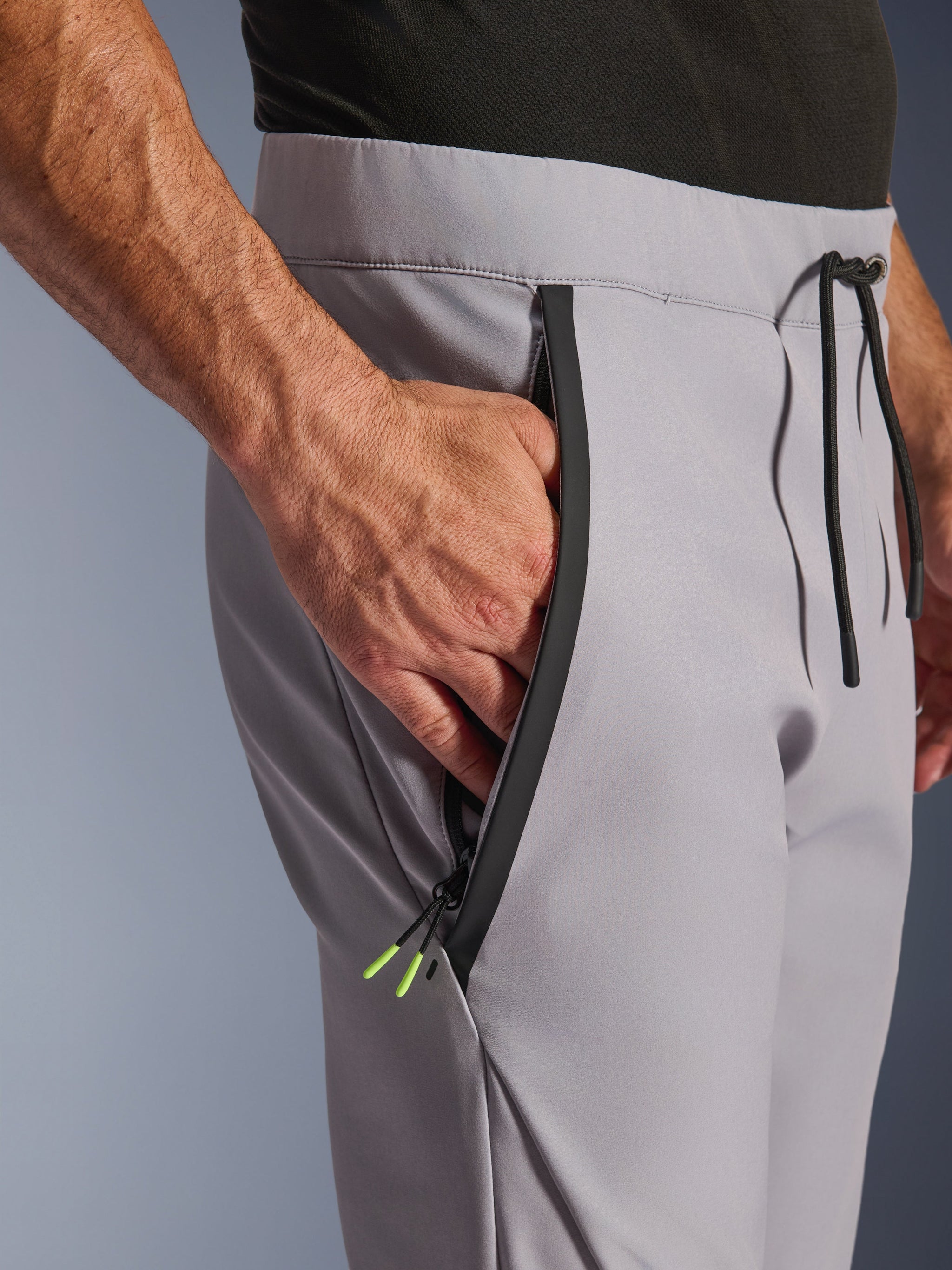 Alpinestars Aeroshell Pants, Mid Gray Yellow Fluo, close-up of zipped front pocket and waist, black taped zipper with yellow fluo tips, elastic waistband with black drawstring, crossover sports softshell motorcycle pants