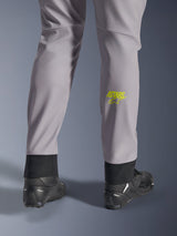 Alpinestars Aeroshell Pants, Mid Gray with Yellow Fluo Astars logo on the calf, shown from the back wearing black motorcycle shoes, featuring an elastic lower hem and a modern tapered silhouette
