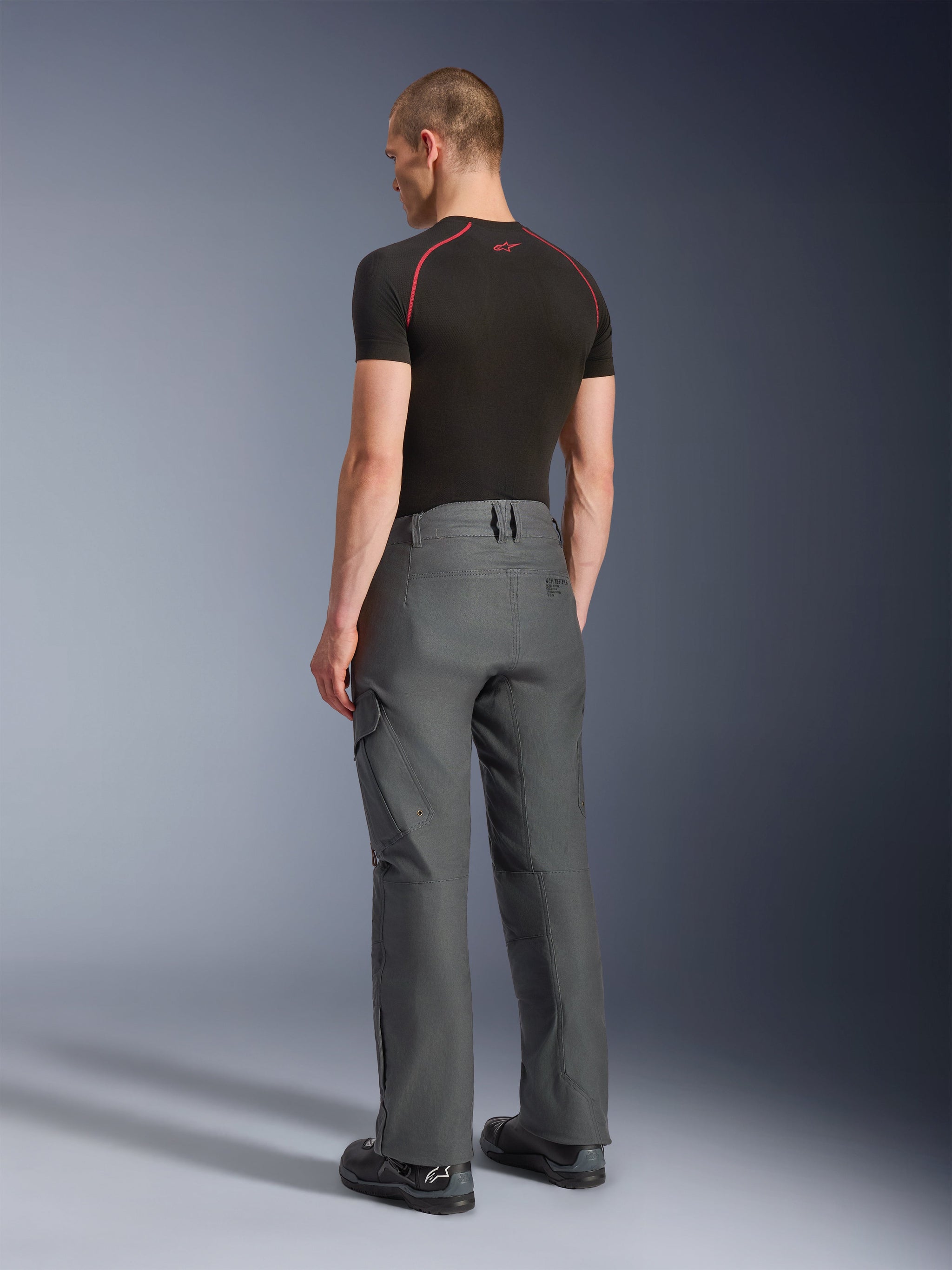 Alpinestars Borrego Drystar® Pants, Adventure Motorcycle Pants, Anthracite Gray, rear view, featuring a waxed-canvas look with cargo pockets, paired with a black t-shirt and riding boots, durable design for road and adventure touring