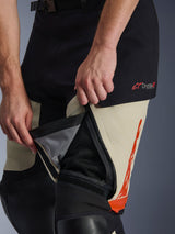 Alpinestars Halo Pro Drystar® XF Laminated Pants, Mastic Black, close-up detail of zippered thigh vent unzipped to reveal internal mesh panel for airflow, featuring red Drystar XF logo and orange graphic accents