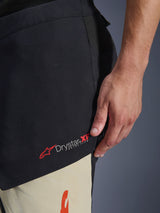 Alpinestars Halo Pro Drystar® XF Laminated Pants, adventure motorcycle pants in Mastic Black, close-up of the side thigh showing the red and white Drystar XF Extra Flow logo, textile construction with mixed color panels.
