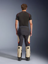 Alpinestars Halo Pro Drystar® XF Laminated Pants, Mastic Black, rear view on a model, black and beige color blocking with orange logos, adventure motorcycle touring pants with durable textile construction and adjustable calf sections