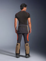 Alpinestars Halo Pro Drystar® XF Laminated Pants, Walnut Rust Black adventure motorcycle pants, back view on a model wearing black boots and a short-sleeved base layer, featuring walnut-colored lower legs, rust orange accents, and black reinforced panels.