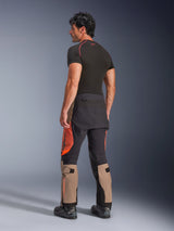 Alpinestars Halo Pro Drystar® XF Laminated Pants in Walnut Rust Black, back view of a male model wearing adventure motorcycle pants with tan, orange, and black panels, styled with a black short-sleeve base layer and black motorcycle boots, highlighting technical outdoor riding gear