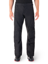 Alpinestars ST-1 Waterproof Pants, Black Motorcycle Touring Pants, front view featuring vertical zippered thigh pockets and adjustable waist tabs, worn with black red-soled boots, plain white background