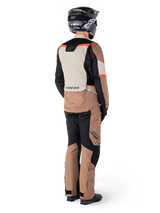 Alpinestars ST-1 Waterproof Pants, Dark Khaki Sand Black Red Fluo, adventure touring motorcycle gear seen from the back, worn with matching jacket, black helmet, and boots, durable textile construction with red accents