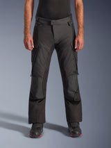 Alpinestars Andes V4 Drystar Pants, Motorcycle Adventure Touring Pants, Black with gray panels, featuring reinforced knee patches and thigh cargo pockets, worn with black riding boots, waterproof textile construction for all-weather riding