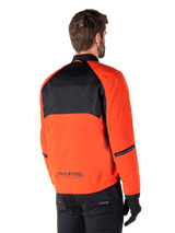 Rear view of a rider wearing the Alpinestars Mootant Waterproof Parka in Spicy Orange and Black, featuring a black mesh upper back panel and reflective MO.ST.EQ. branding, modern utilitarian motorcycle jacket.