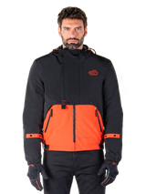 Alpinestars Mootant Waterproof Parka, modular motorcycle jacket in Spicy Orange and Black, worn by a model with matching gloves, features a hooded design with two-tone panels, front zipper, and adjustable cuffs, urban contemporary riding apparel
