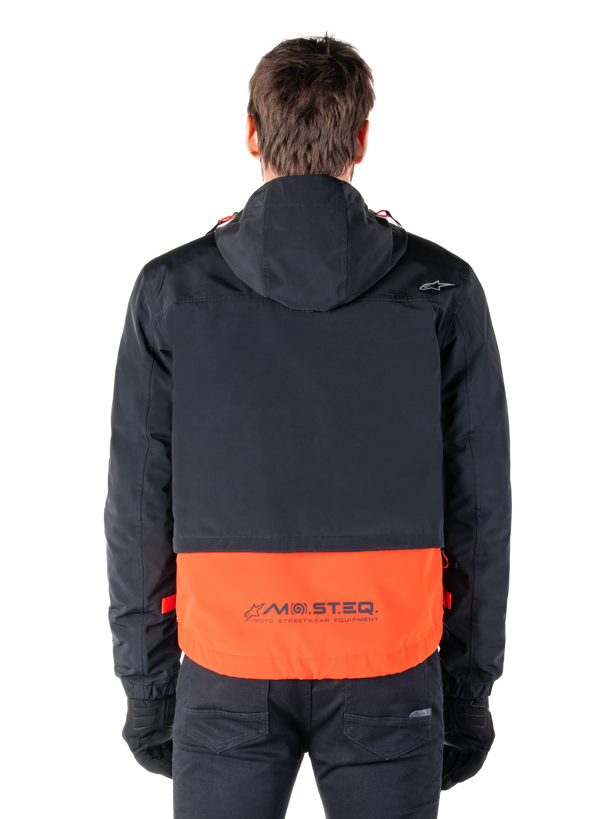 Alpinestars Mootant Waterproof Parka in Spicy Orange and Black, rear view showing black upper with hood and orange lower panel featuring the MO.ST.EQ. wordmark, functional motorcycle streetwear.