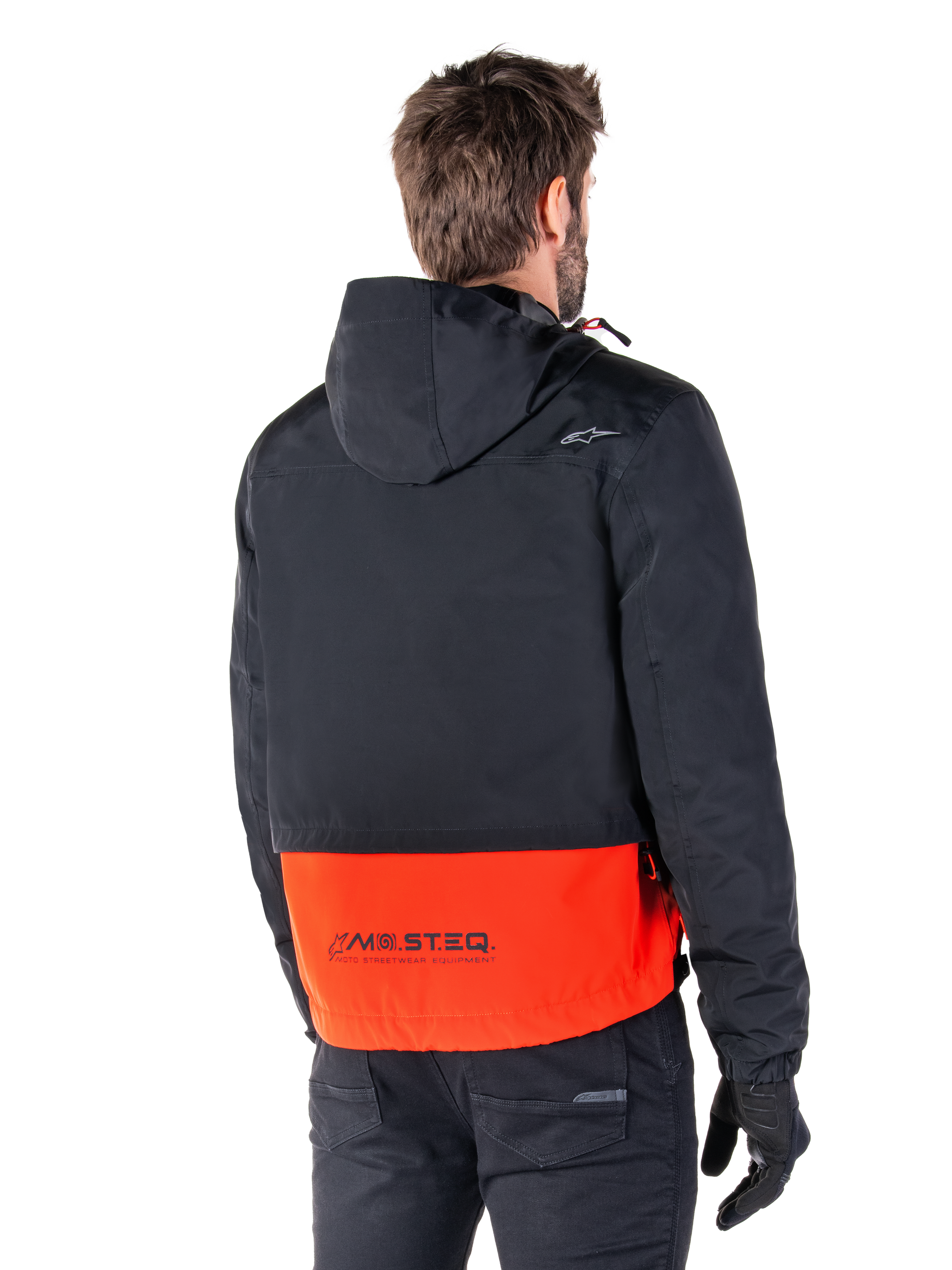 Alpinestars Mootant Waterproof Parka, Spicy Orange and Black, rear view on a male model, features a hooded black upper and bright orange lower section with MO.ST.EQ. branding, urban contemporary motorcycle jacket worn with black pants and gloves