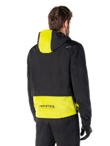 Alpinestars Mootant Waterproof Parka, Rear View, Lime Punch and Black, featuring a black upper body with a lime yellow hood panel and lower back, MO.ST.EQ. branding on the hem, worn with black riding pants and gloves, urban contemporary motorcycle jacket