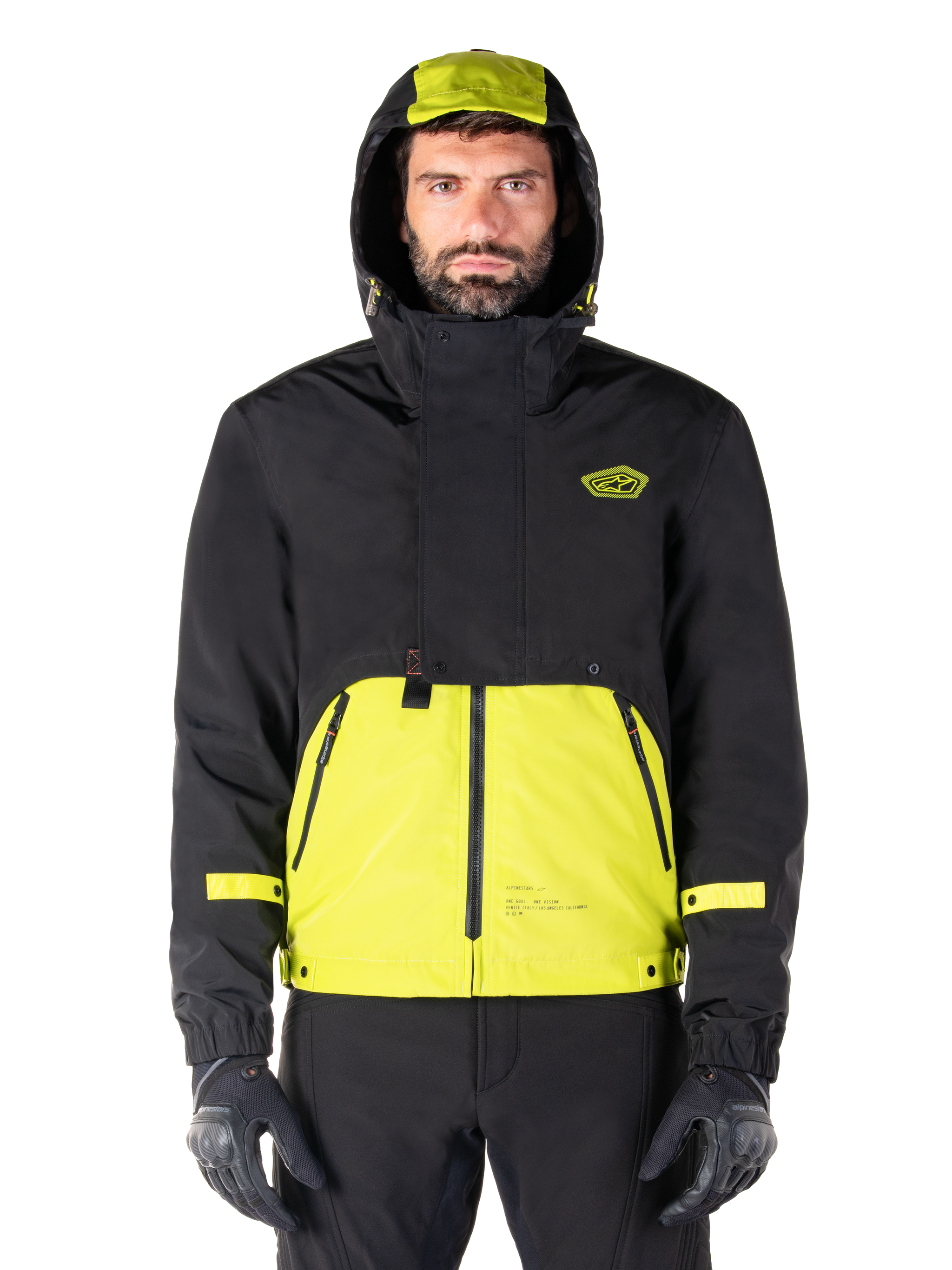 Alpinestars Mootant Waterproof Parka, Lime Punch Black motorcycle jacket, front view, modular 3-in-1 design with black upper and bright lime green lower section, featuring a drawstring hood and chest logo, worn with black pants and riding gloves