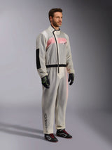 Alpinestars Kart Rain Suit, Clear waterproof karting oversuit, semi-transparent material showing a pink and white racing suit underneath, featuring a black asymmetric zipper, reinforced elbow patch, and black waist band, worn with black karting gloves and racing shoes.